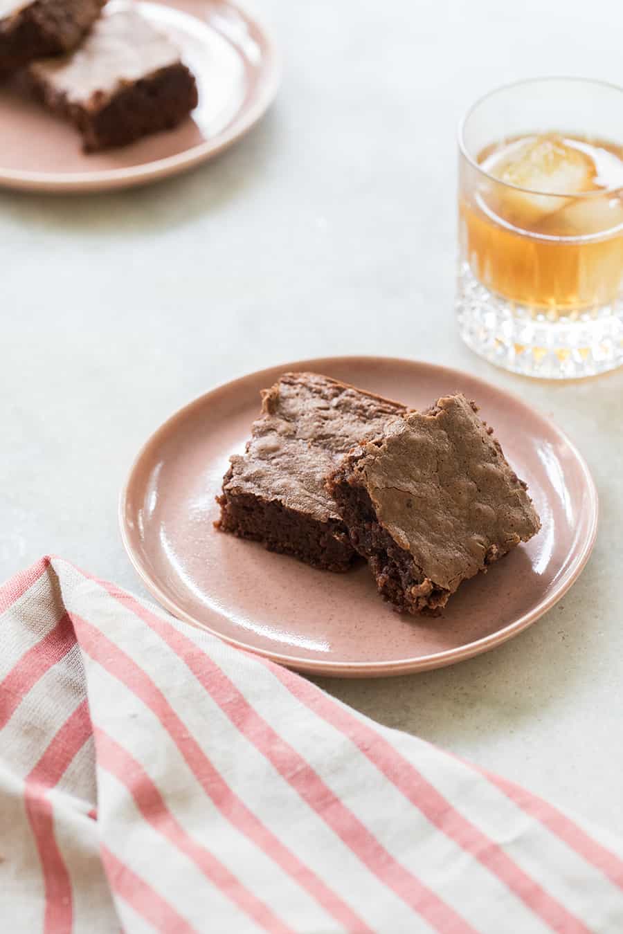 Chocolate brownies on a pink plate with a glass of bourbon. - bourbon brownies