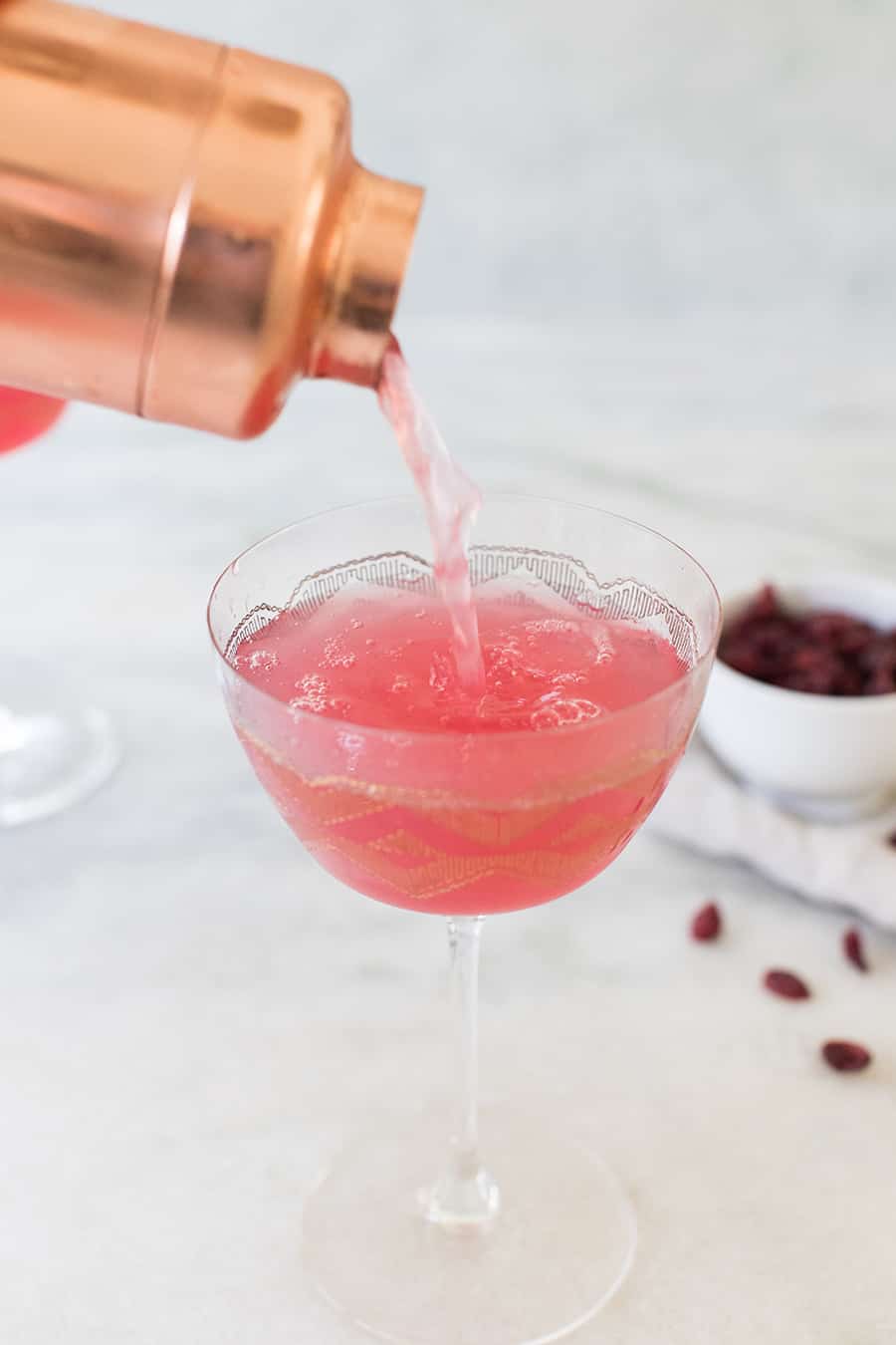 cranberry martini being poured into a glass