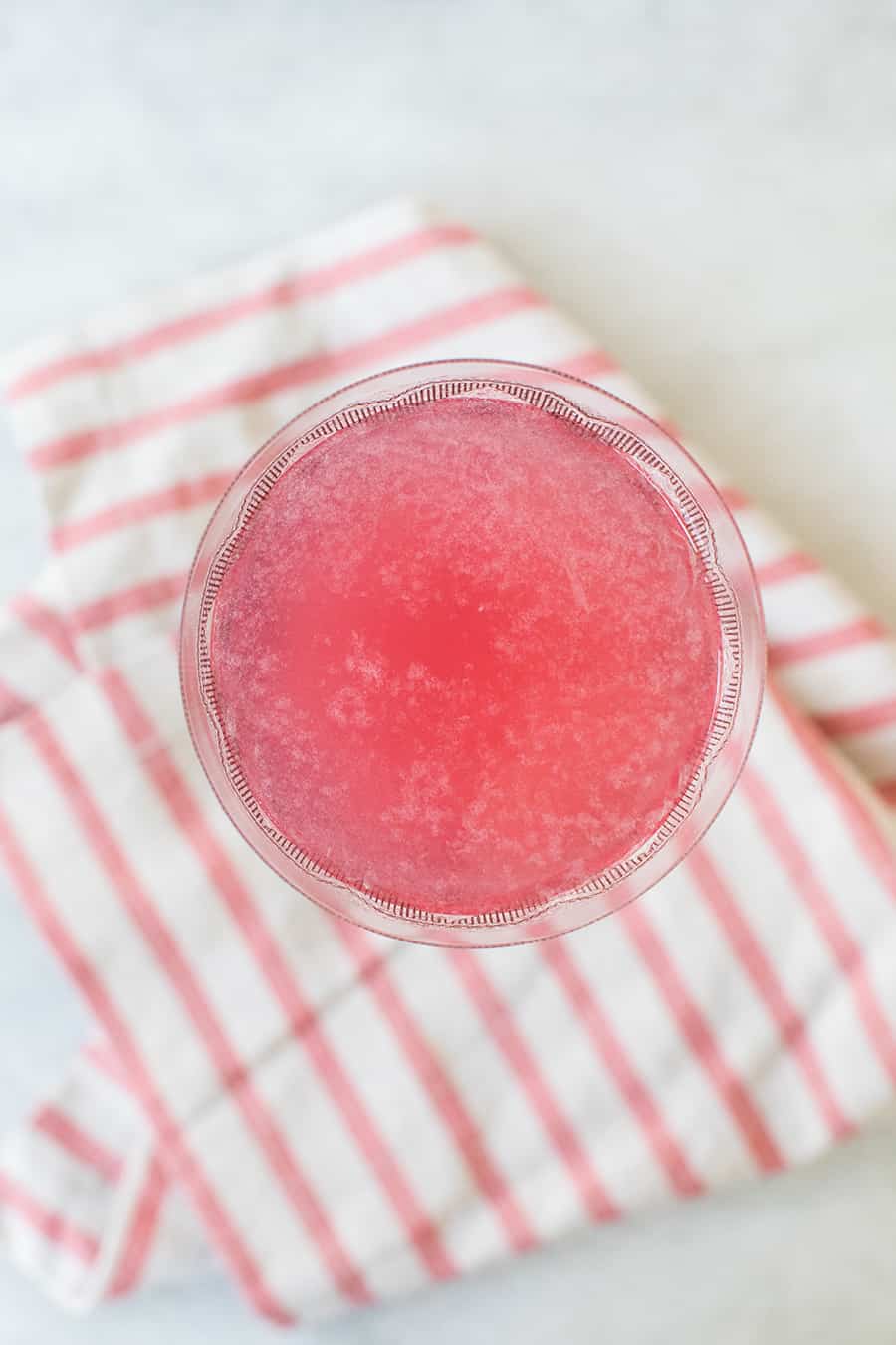 top down shot of cranberry martini on a pink napkin.