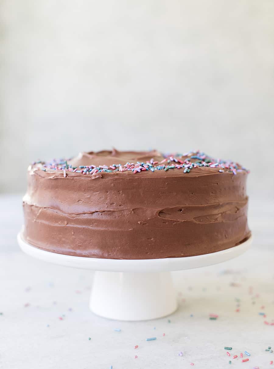 Side shot of devil's food cake on a white cake stand