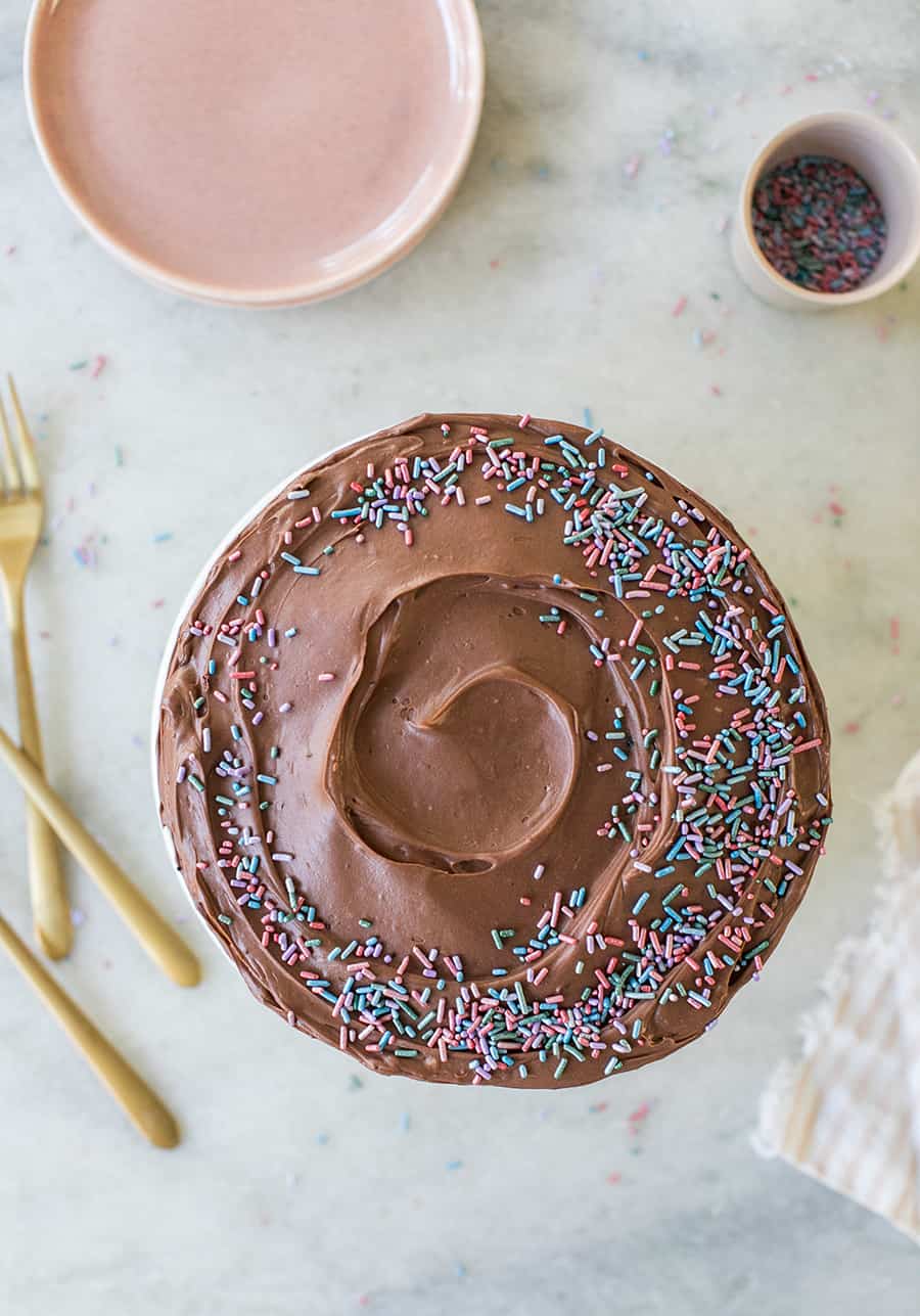 devil's food cake on marble table with gold silverware, pink plates and sprinkles. 