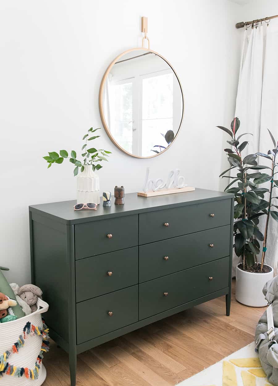 Olive green dresser with plant and a gold mirror.