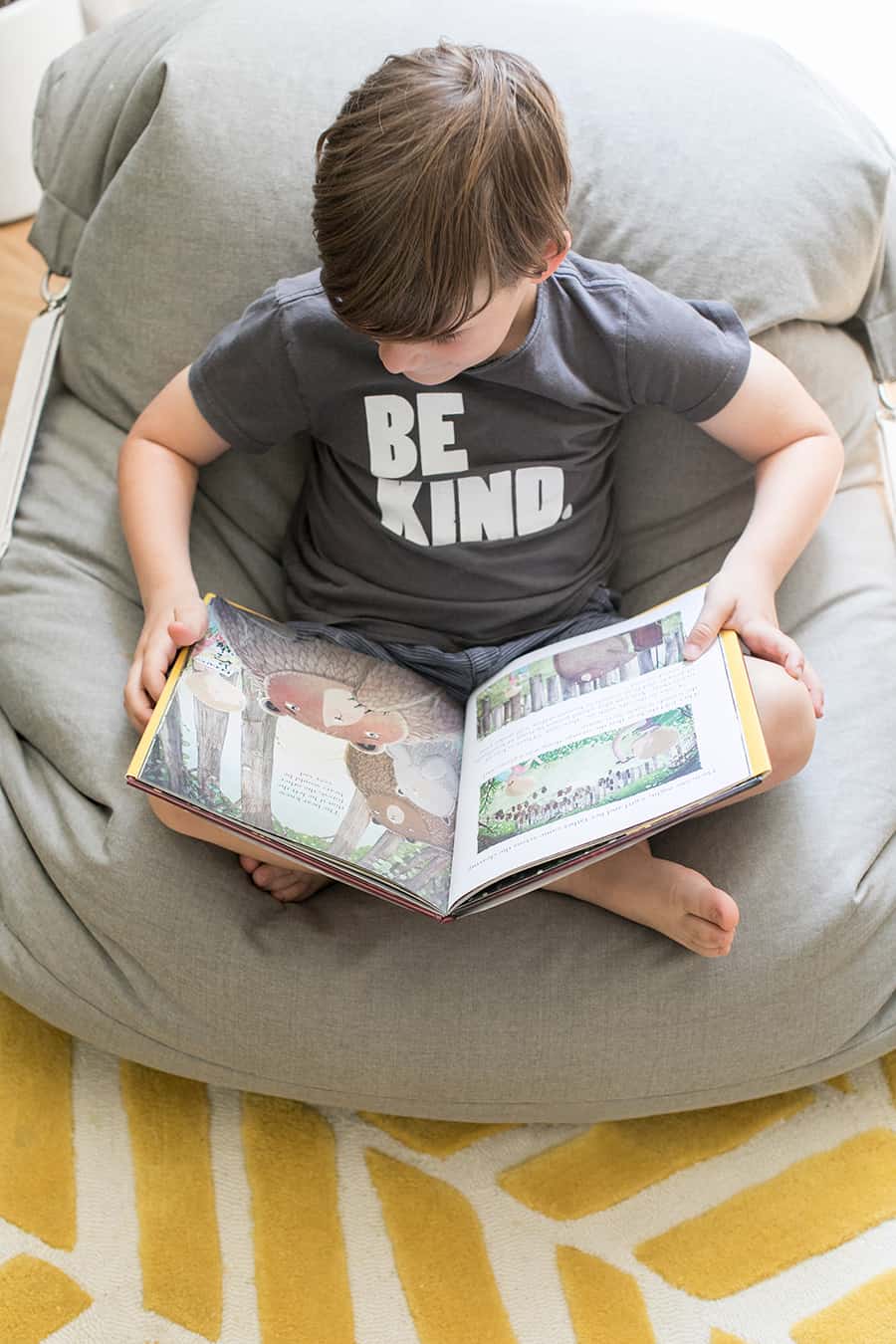 Little boy in a beanbag chair reading a book.