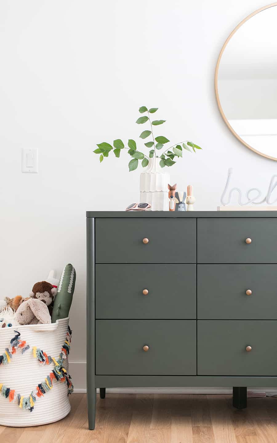 Boys room with an olive green dresser and a gold mirror. 