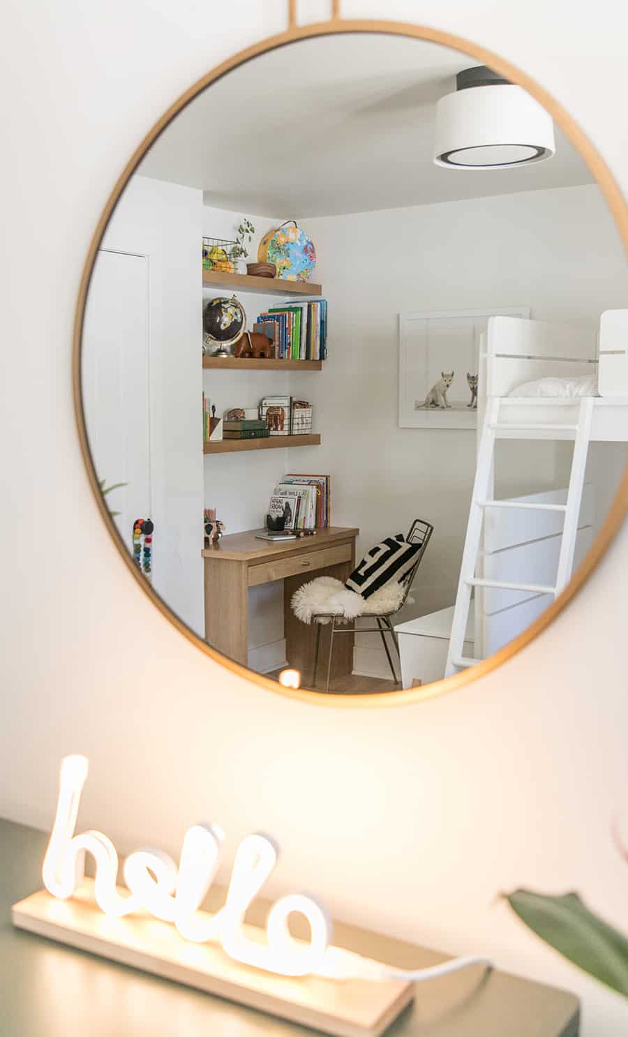 Gold mirror looking at a built in desk and bunk beds.