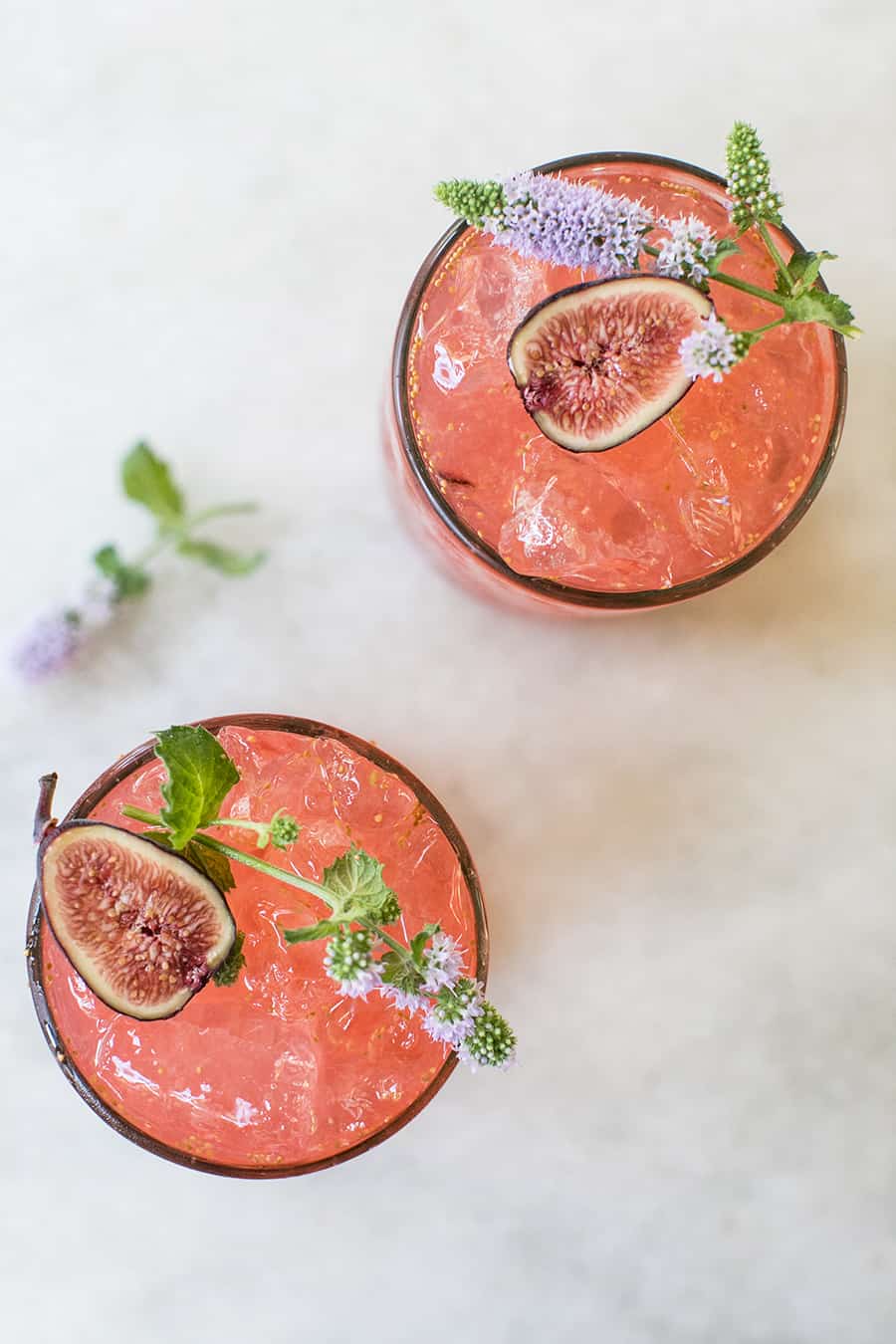 Pink cocktail with figs and edible flowers.