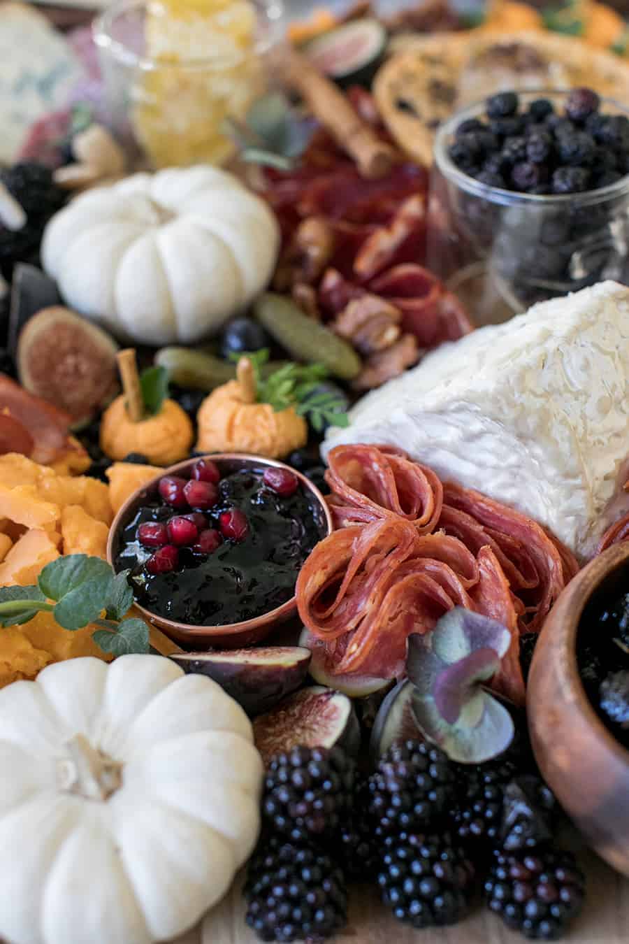 Halloween Meat and Cheese Board with pumpkins, berries, pickles, olives, cheese and meat. 