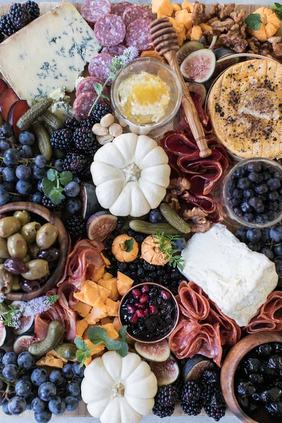 Halloween Meat and Cheese Board with pumpkins, berries, pickles, olives, cheese and meat.