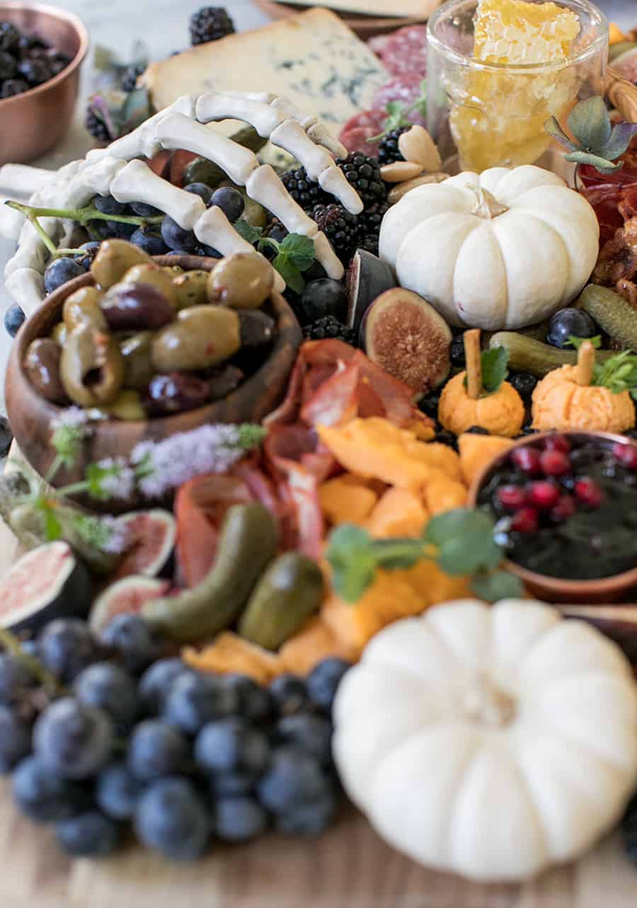 Skeleton hand grabbing the meat and cheese on a Halloween cheese board. 