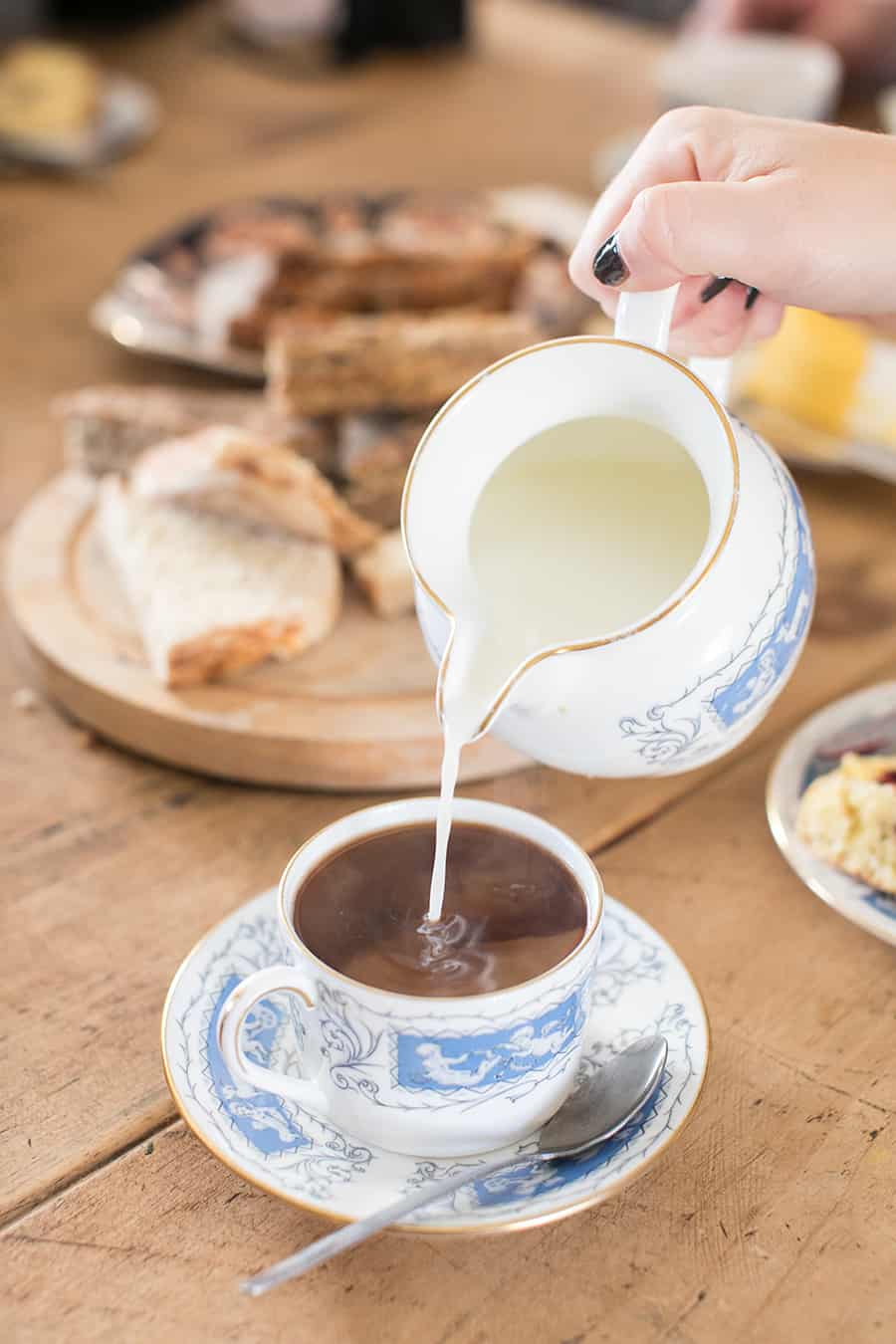 Pouring cream into a tea cup.