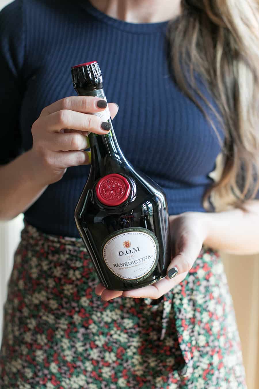 Girl holding a bottle of Bénédictine. 