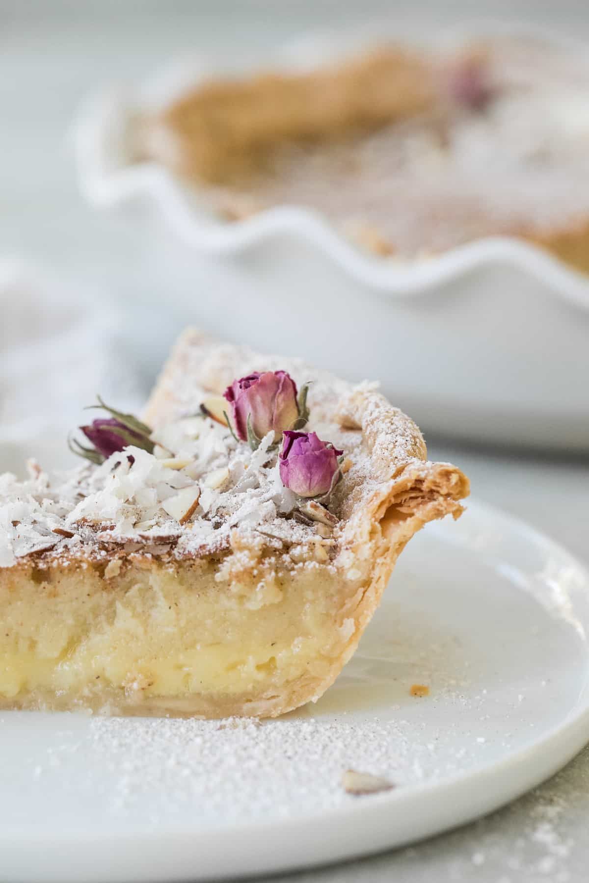 slice of egg custard pie decorated with coconut and flowers - creamy custard, vanilla ice cream, pie dish, egg white, parchment paper
