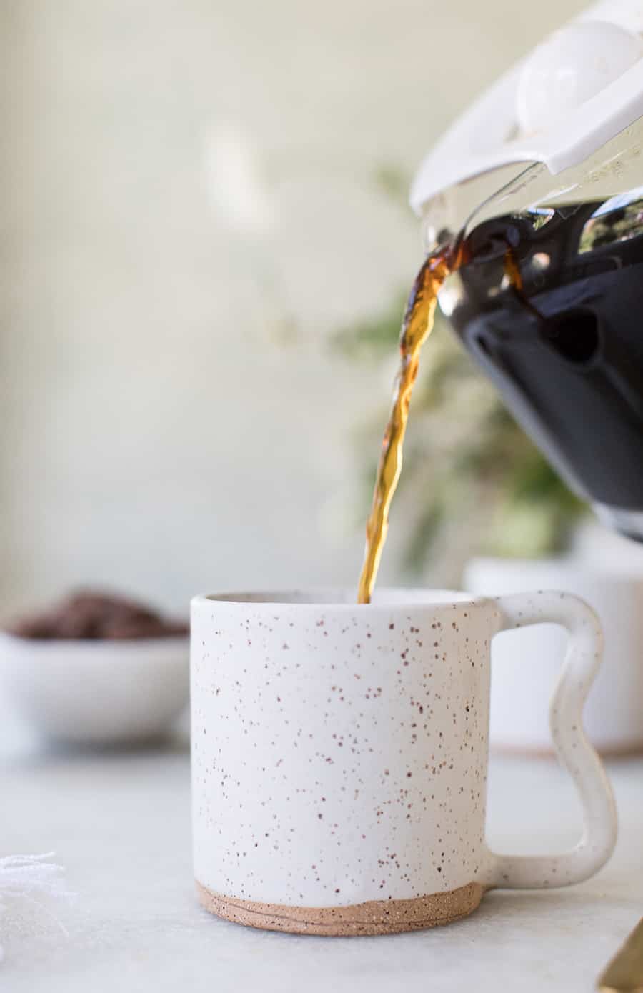 side shot of coffee being poured into a mug