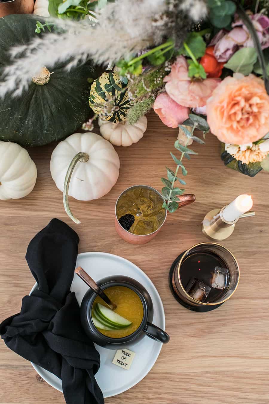 Halloween dinner ideas with soup in a cauldron, pumpkins, flowers, candles. 