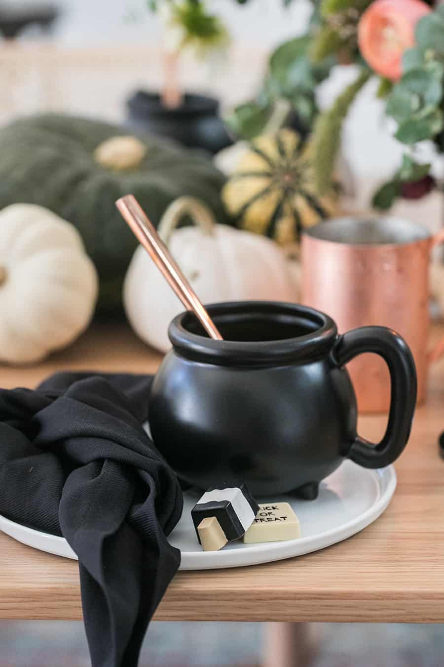 shot of mini mug cauldron with mini chocolates and a black napkin.
