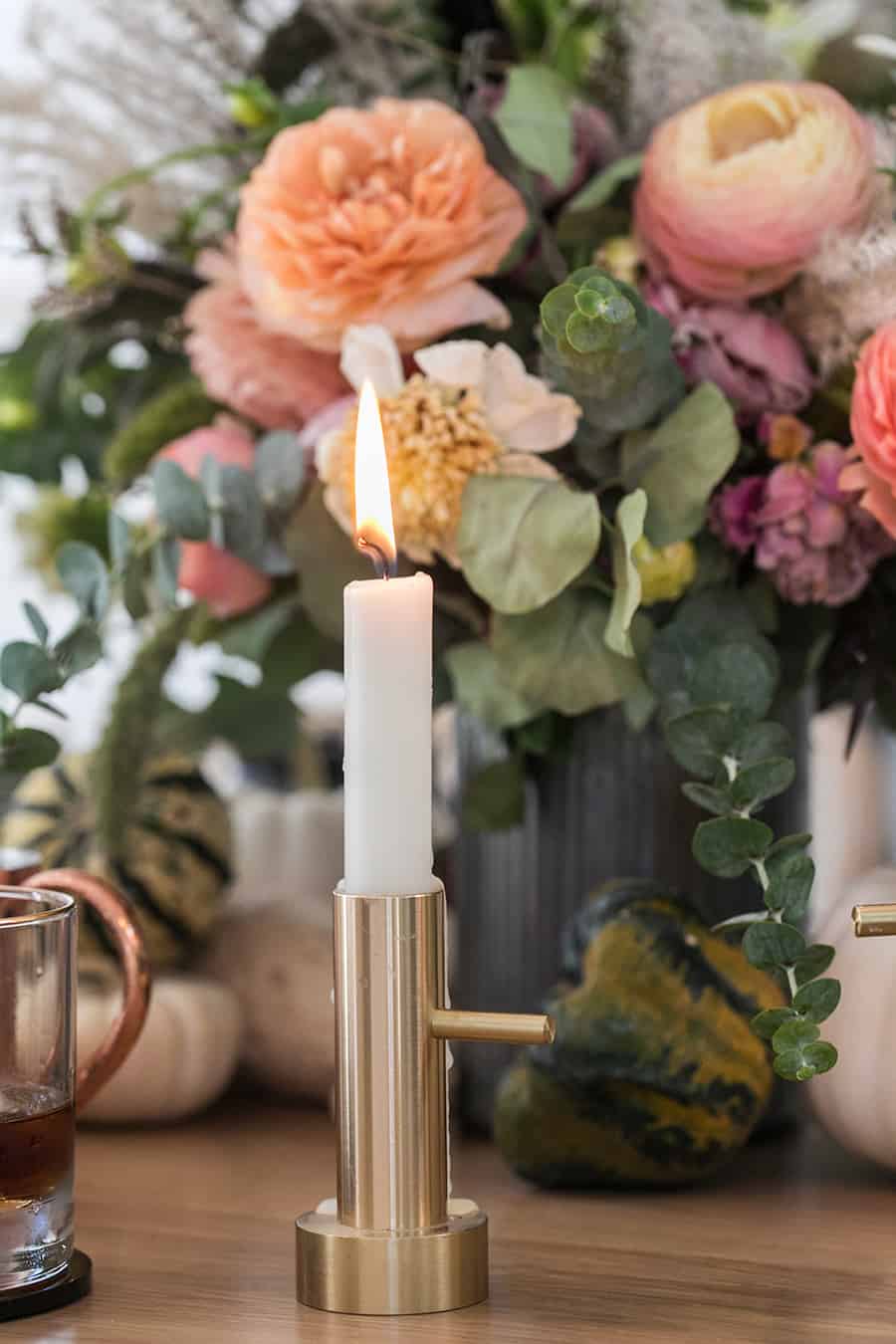 Brass candle stick lit on a charmingly spooky Halloween table.