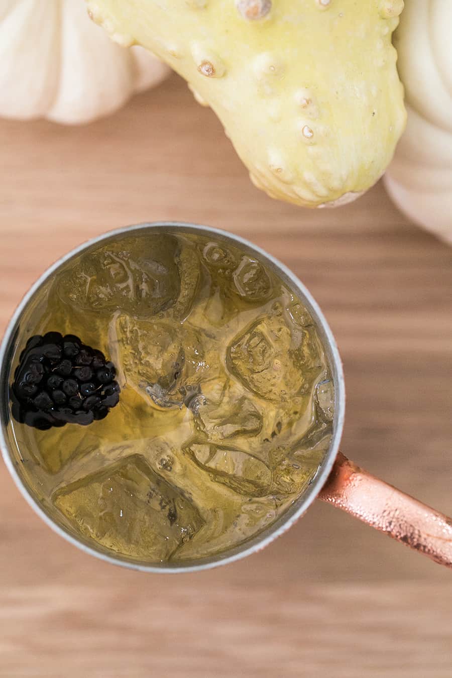 Cocktail in a copper mug with a blackberry.