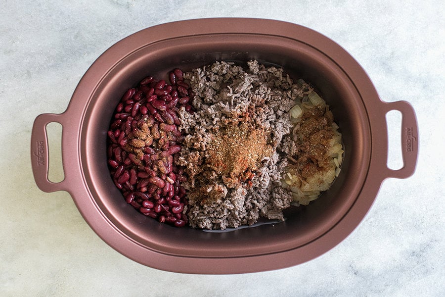 overhead shot of ingredients for best slow cooker chili in a pot - beef broth