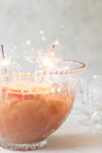 A punch bowl with Spiced Apple Sparkling Holiday Punch recipe and sparklers