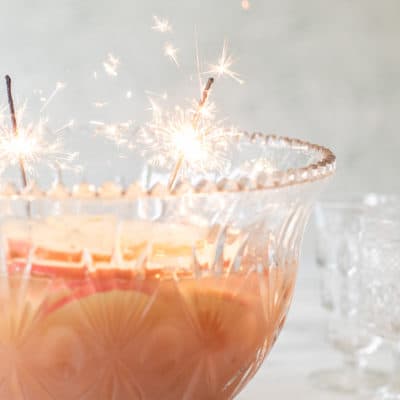 A punch bowl with Spiced Apple Sparkling Holiday Punch recipe and sparklers