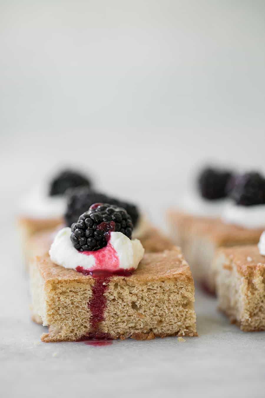 Brown sugar cake with whipped cream and a blackberry. 