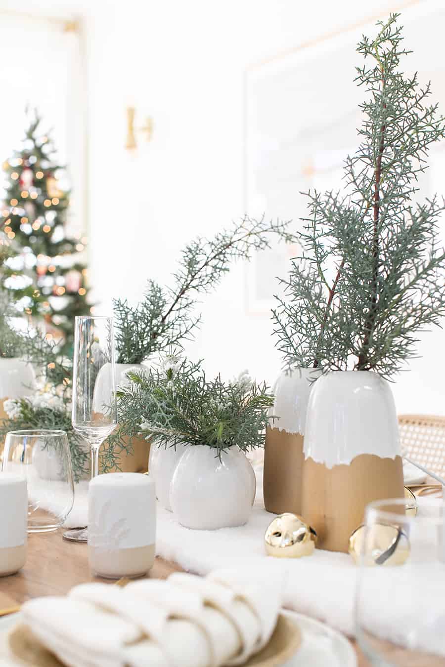 White and gold vases with holiday greens for a Christmas table setting