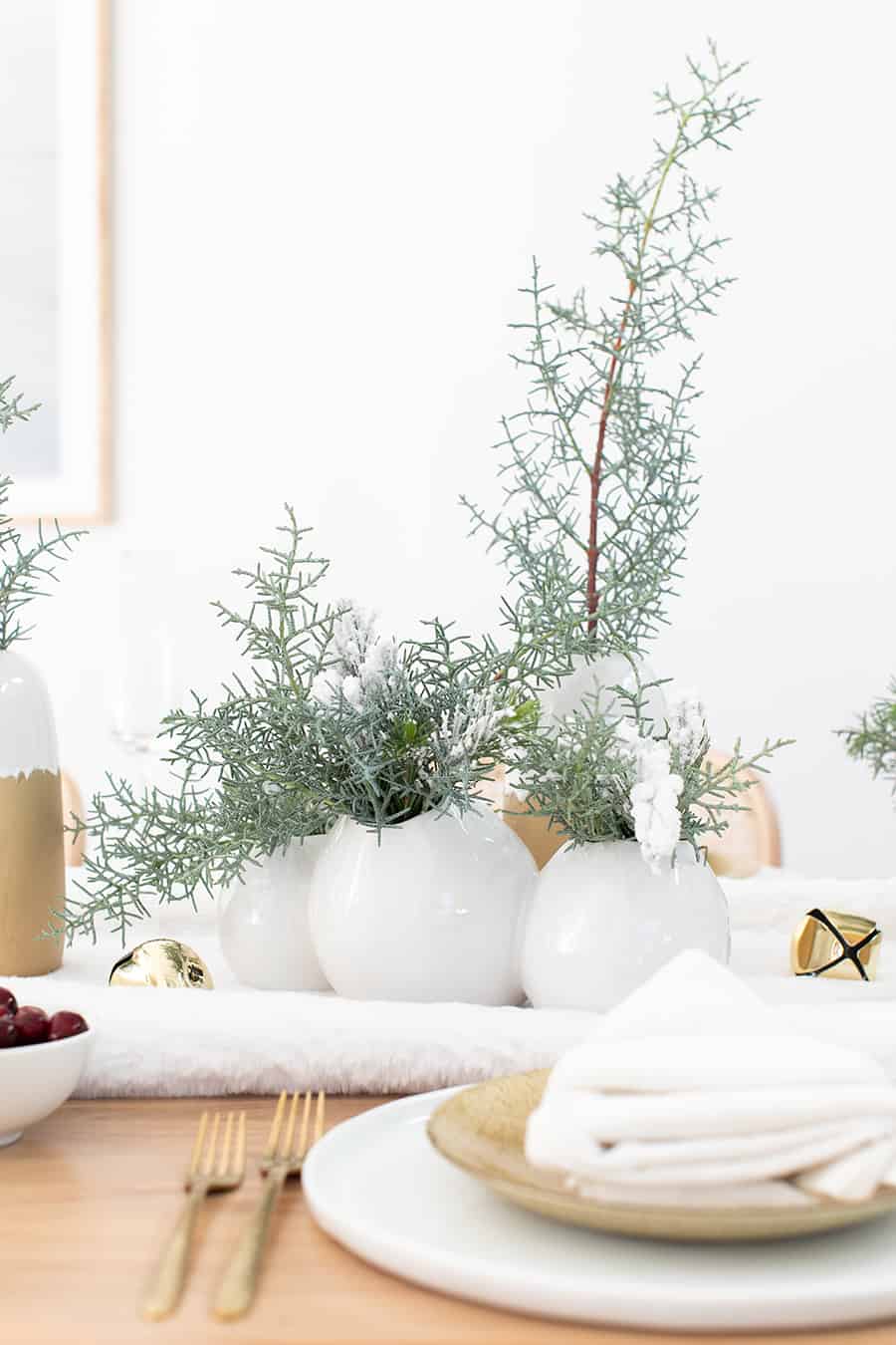 White vases filled with winter greens.