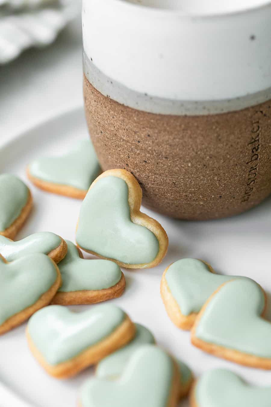 mini heart shaped sugar cookies on a plate with coffee