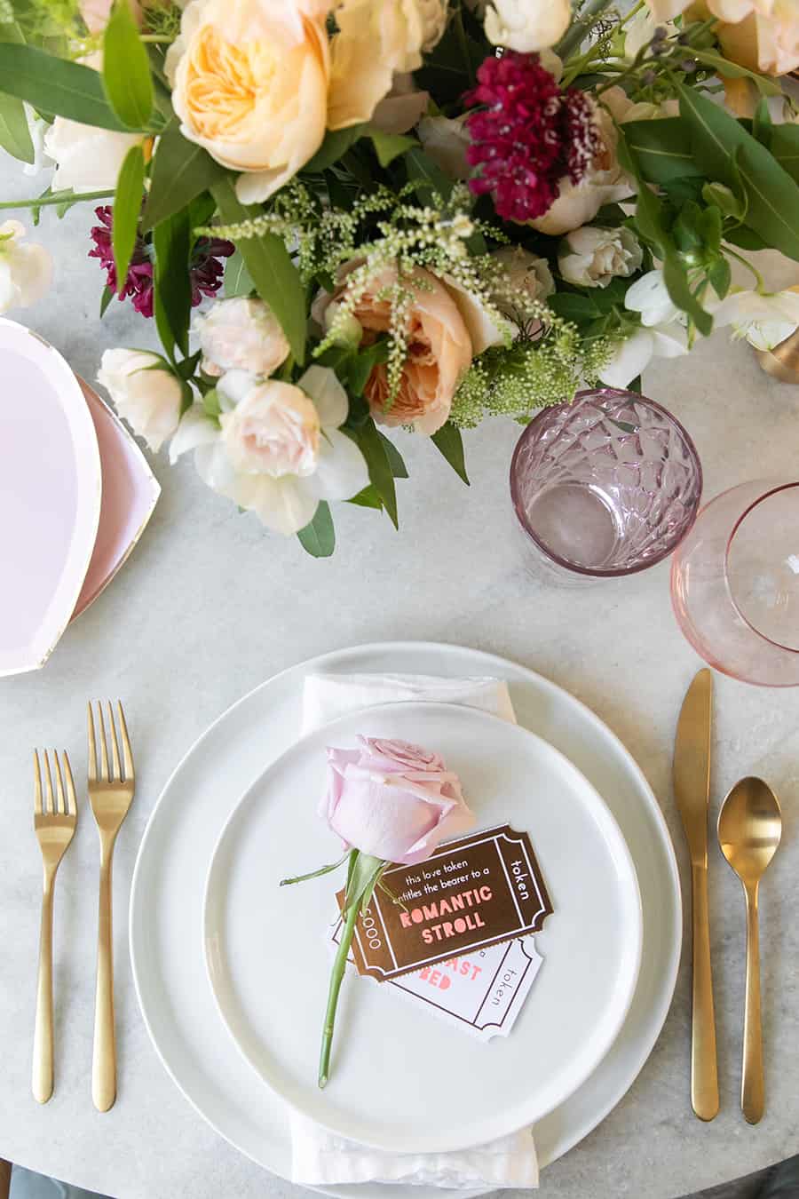 Valentine's Day dinner and table setting with white dishes, gold flatware and romantic stroll token card.