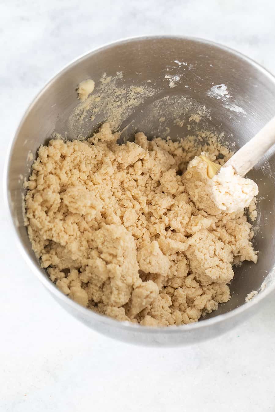 Shortbread dough in a silver mixing bowl with spatula.