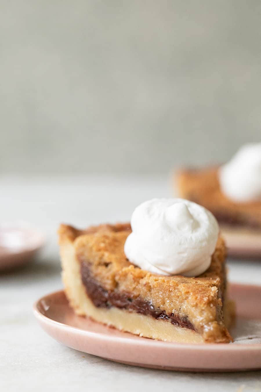 Slice of a chocolate chip cookie pie with whipped cream.
