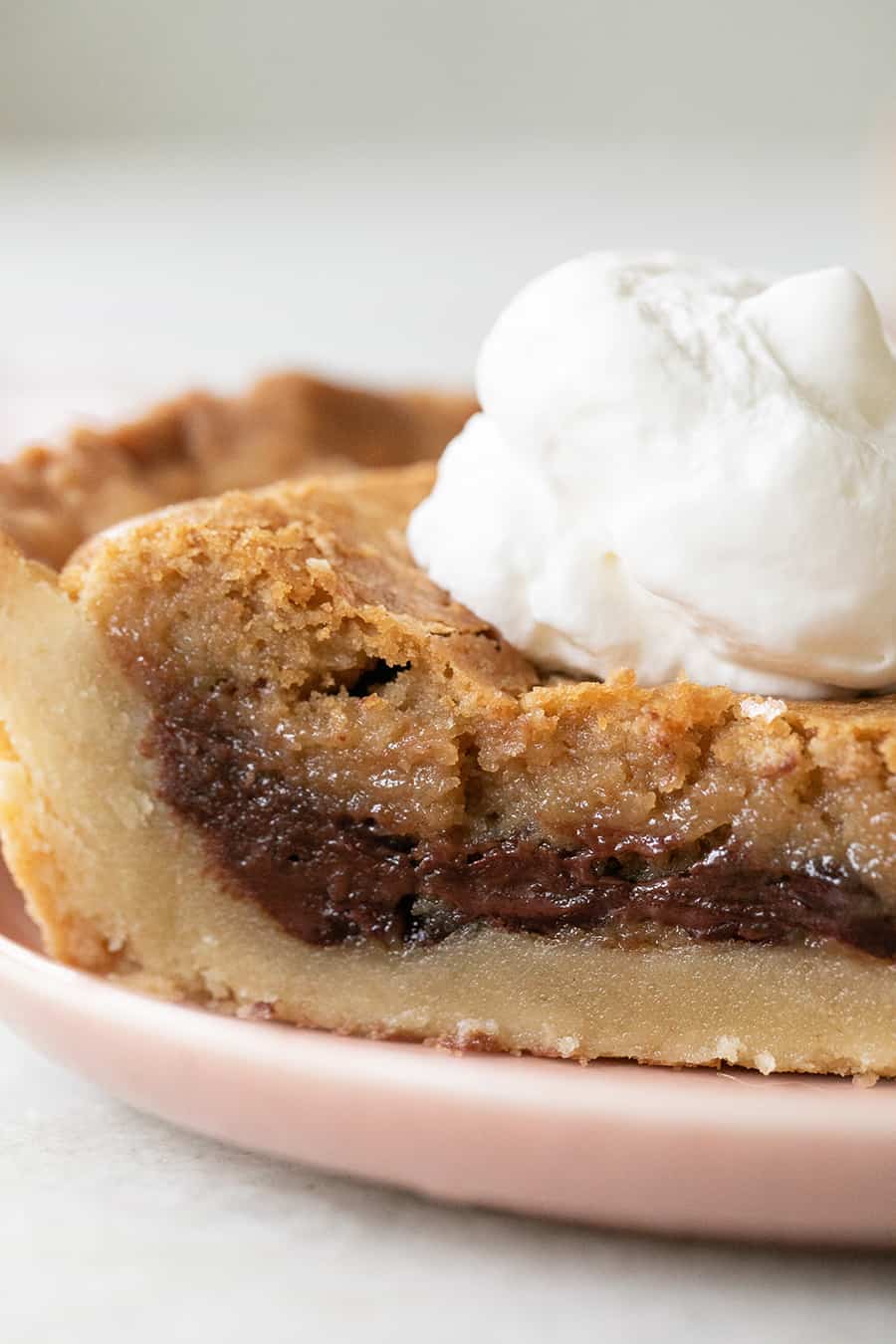 Close-up photo of a chocolate chip cookie pie with shortbread pie crust and whipped cream.