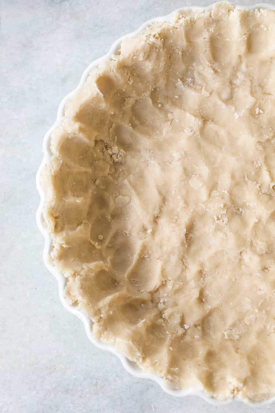 Corteza de tarta de galletas prensada en un plato de tarta blanco