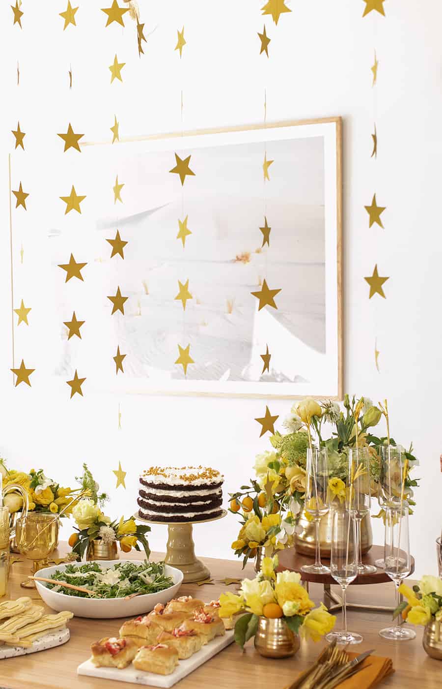 Gold stars hanging from ceiling for Oscar party decorations.