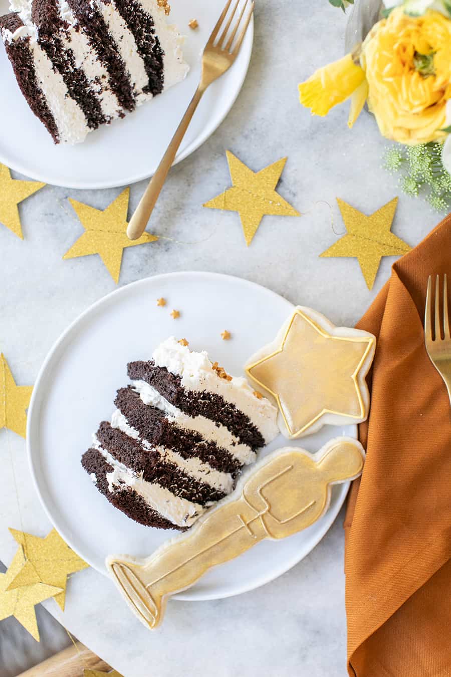 Oscar party tuxedo cake on white plate with cookies.