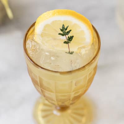 lemonade in yellow glass with thyme sprig