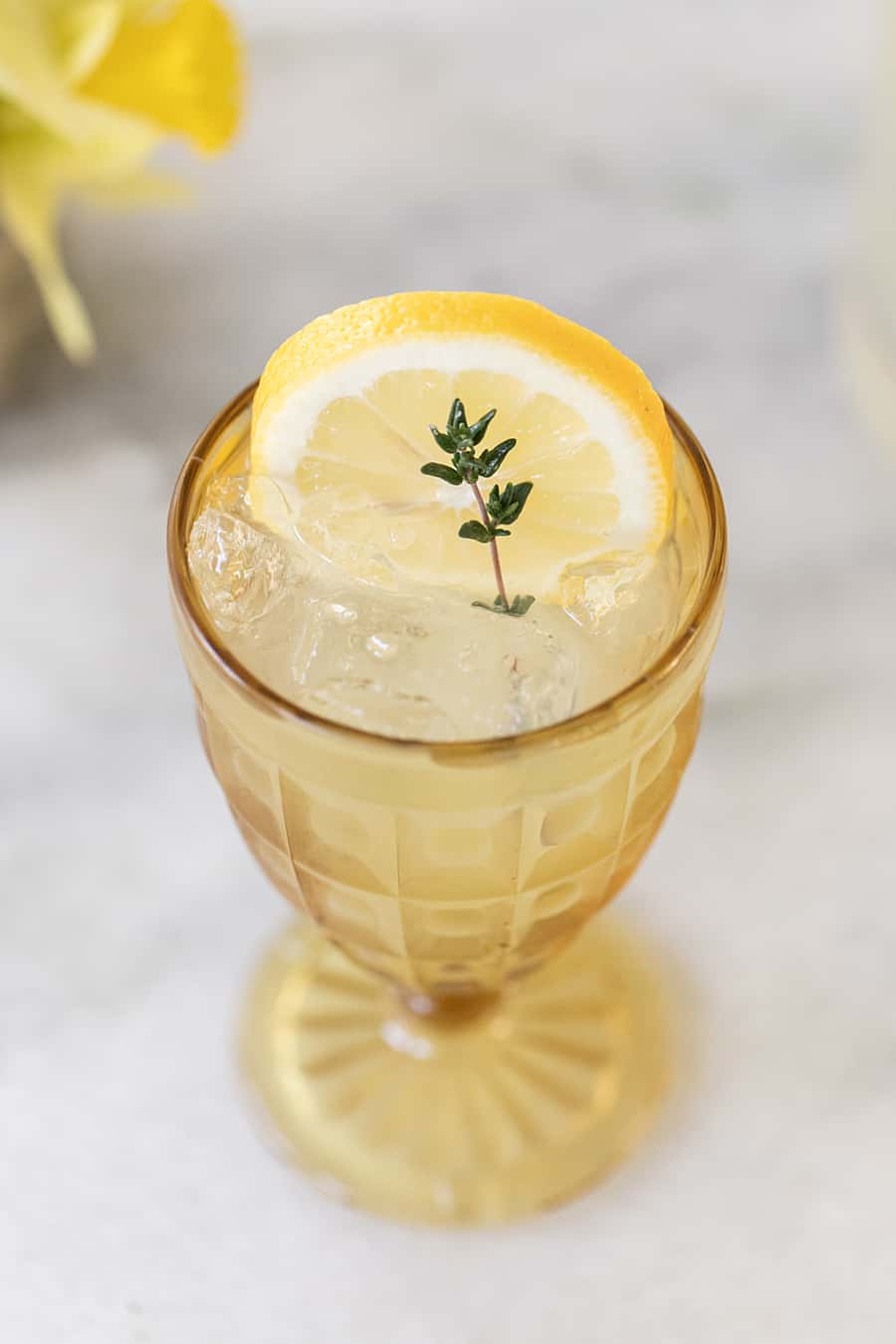 lemonade in yellow glass with thyme sprig