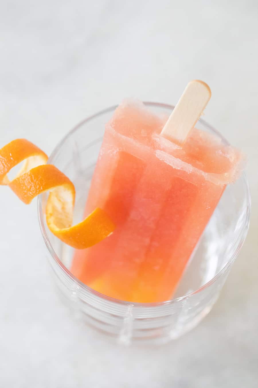 Grapefruit Negroni popsicle in glass with orange rind