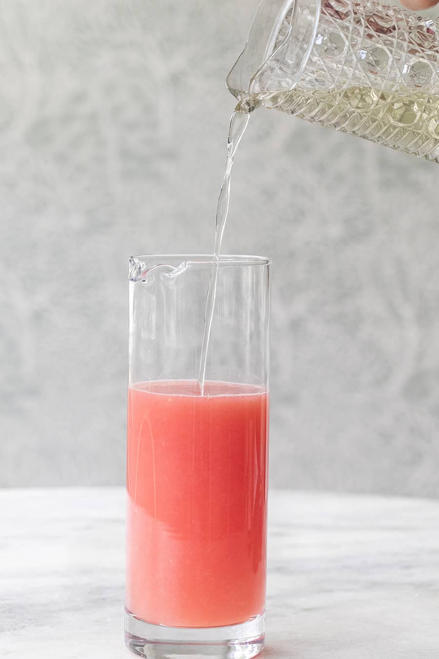 Simple syrup being poured into fresh grapefruit juice
