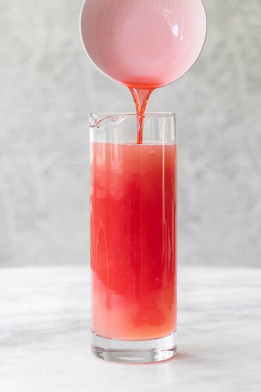 Campari being poured into fresh grapefruit juice for Negroni popsicles