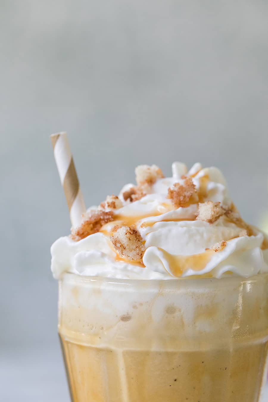 close up picture of a caramel coffee milkshake, with whipped cream and caramel on the top