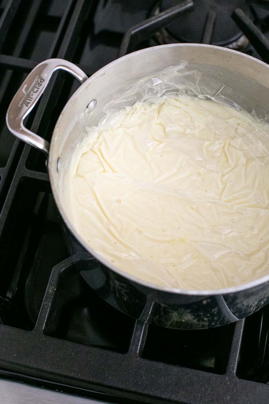 Coconut cream pie in a pot with plastic wrap to keep it from hardening. 