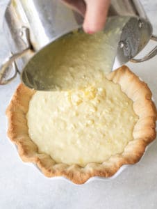 pouring coconut cream pie filling into a pie crust