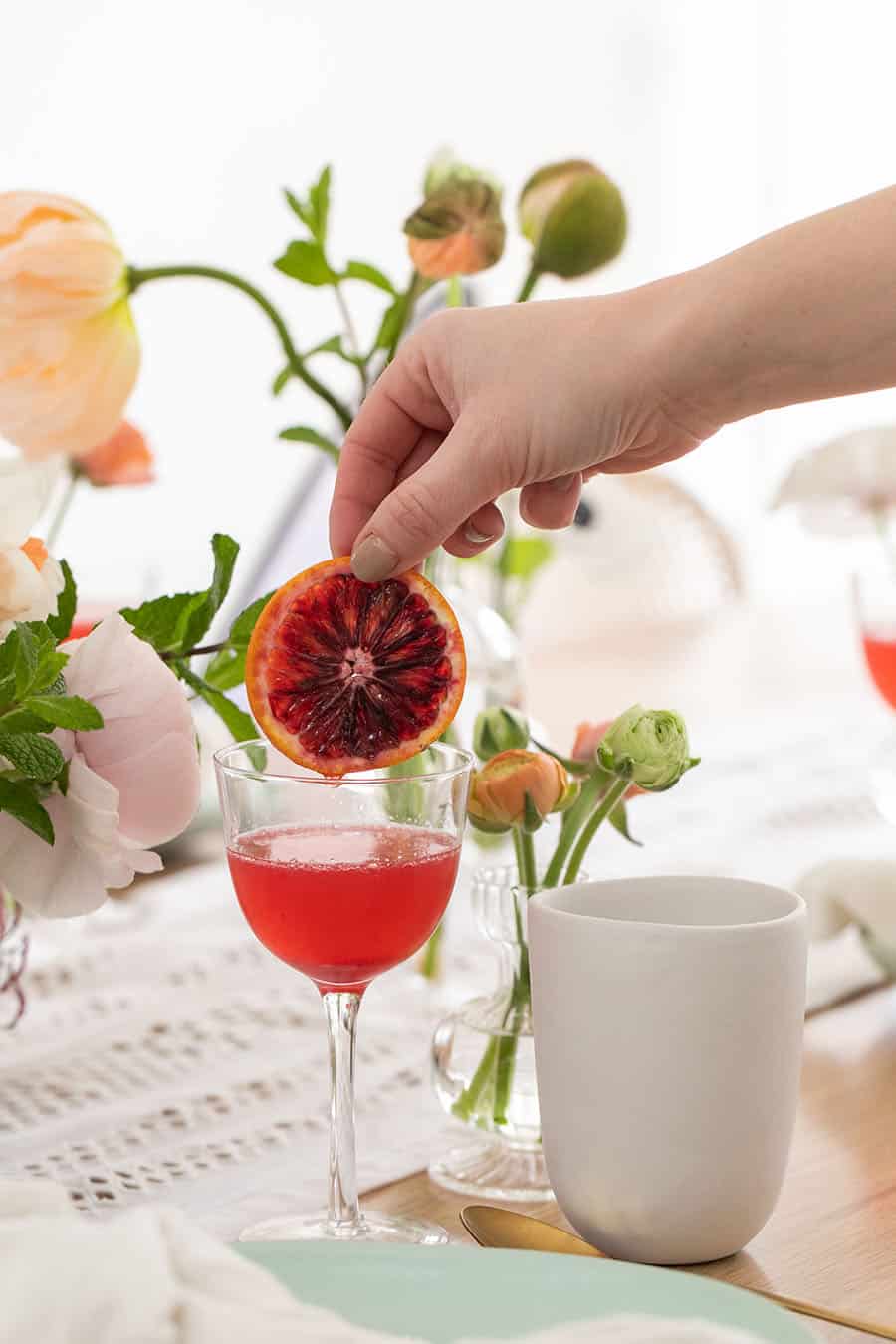 Eden Passante adding a blood orange slice into a blood orange mimosa.