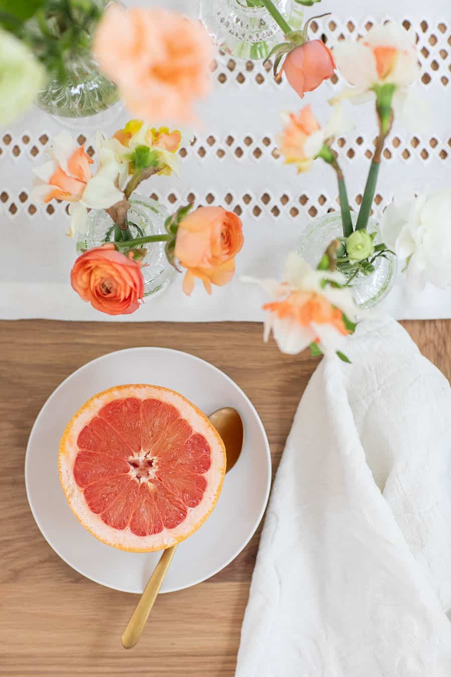 Grapefruit cut in half with a gold spoon.