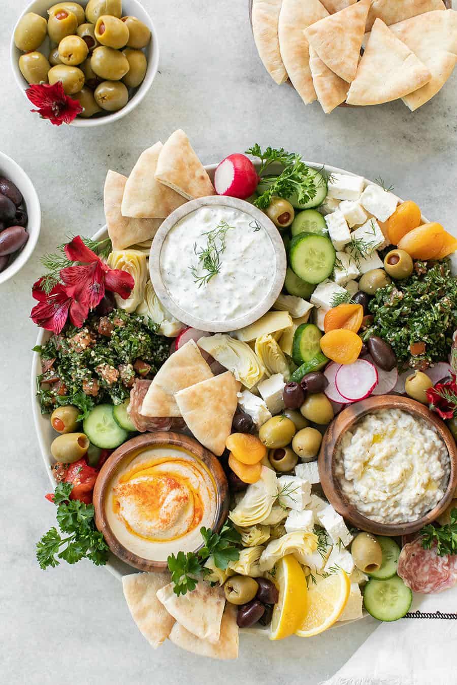 Easy Greek Mezze Platter on a marble table with dips, bread, olives and feta. 