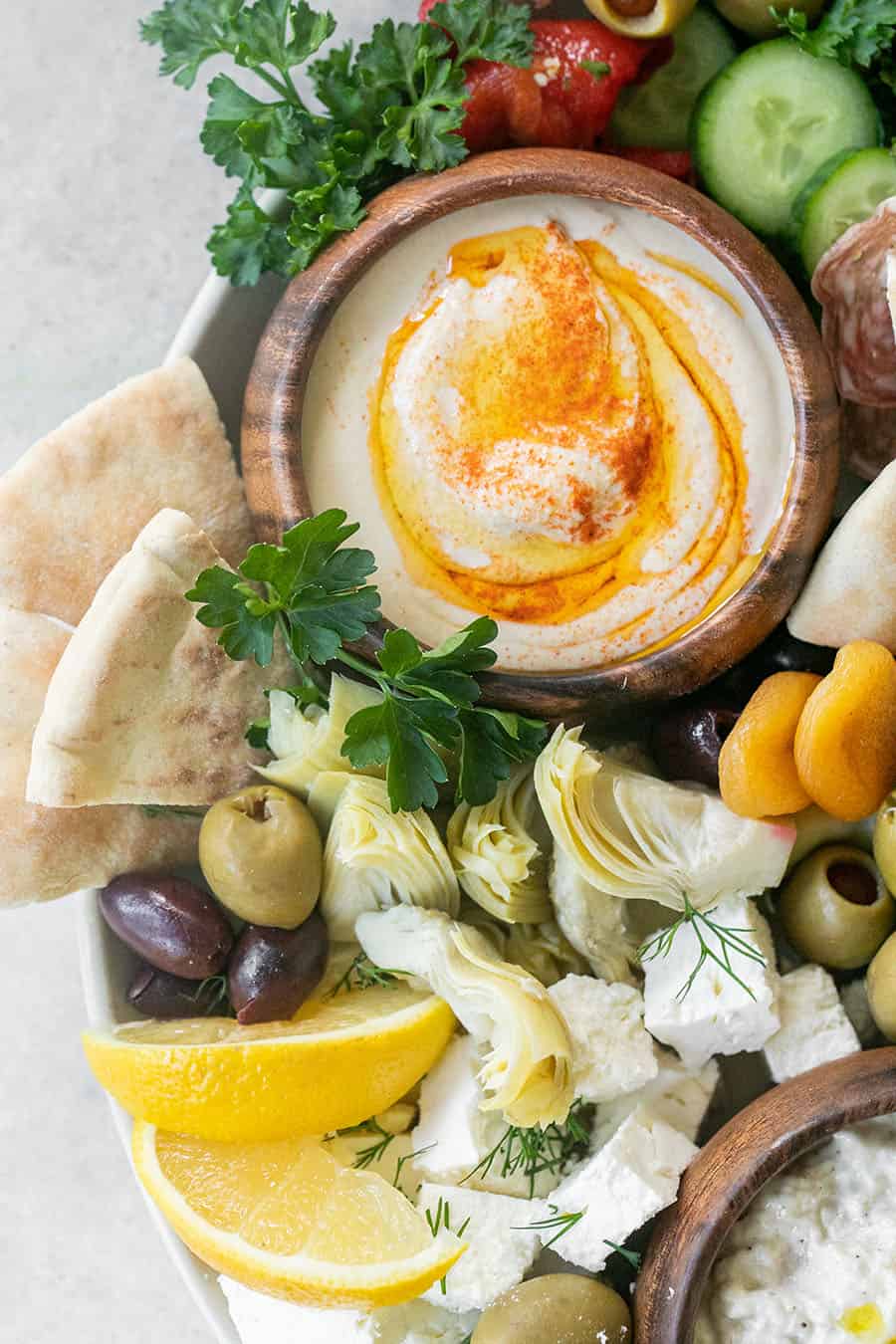 Easy Greek Food Mezze Platter with hummus, lemons, olives, and herbs.