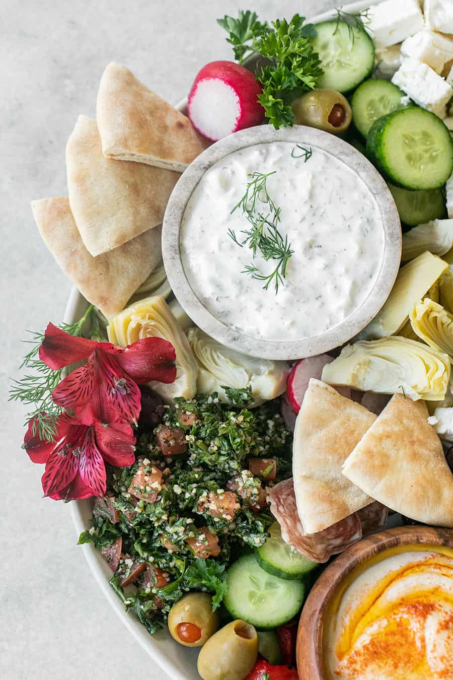 Easy Greek Mezze Platter with yogurt in a bowl and pretty flowers and pita bread.