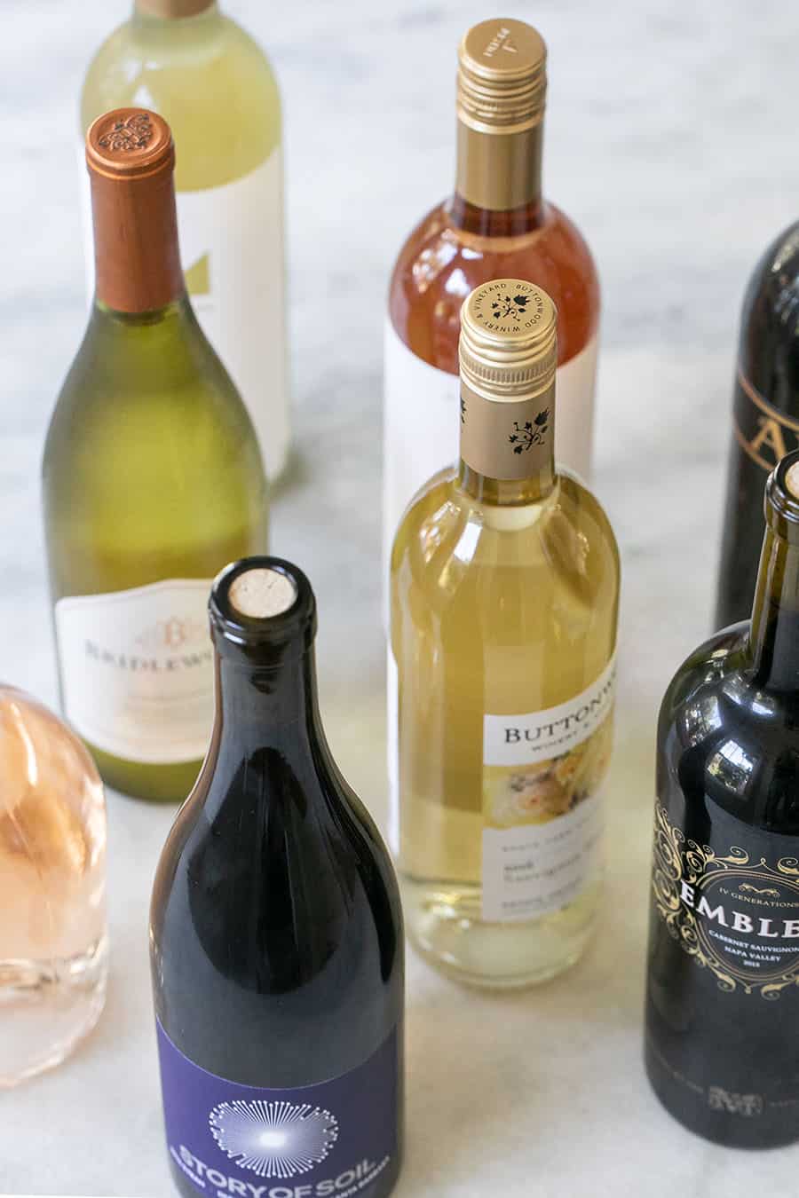 Bottles of red and white wines on a marble table.