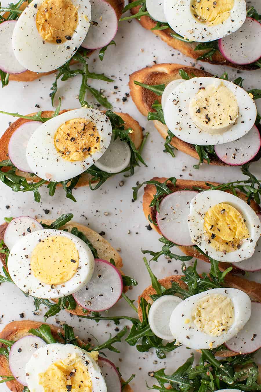 Crostini recipe with hard boiled eggs, radish, arugula and salt and pepper.